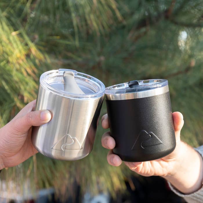 two people holding up stainless steel insulated cups