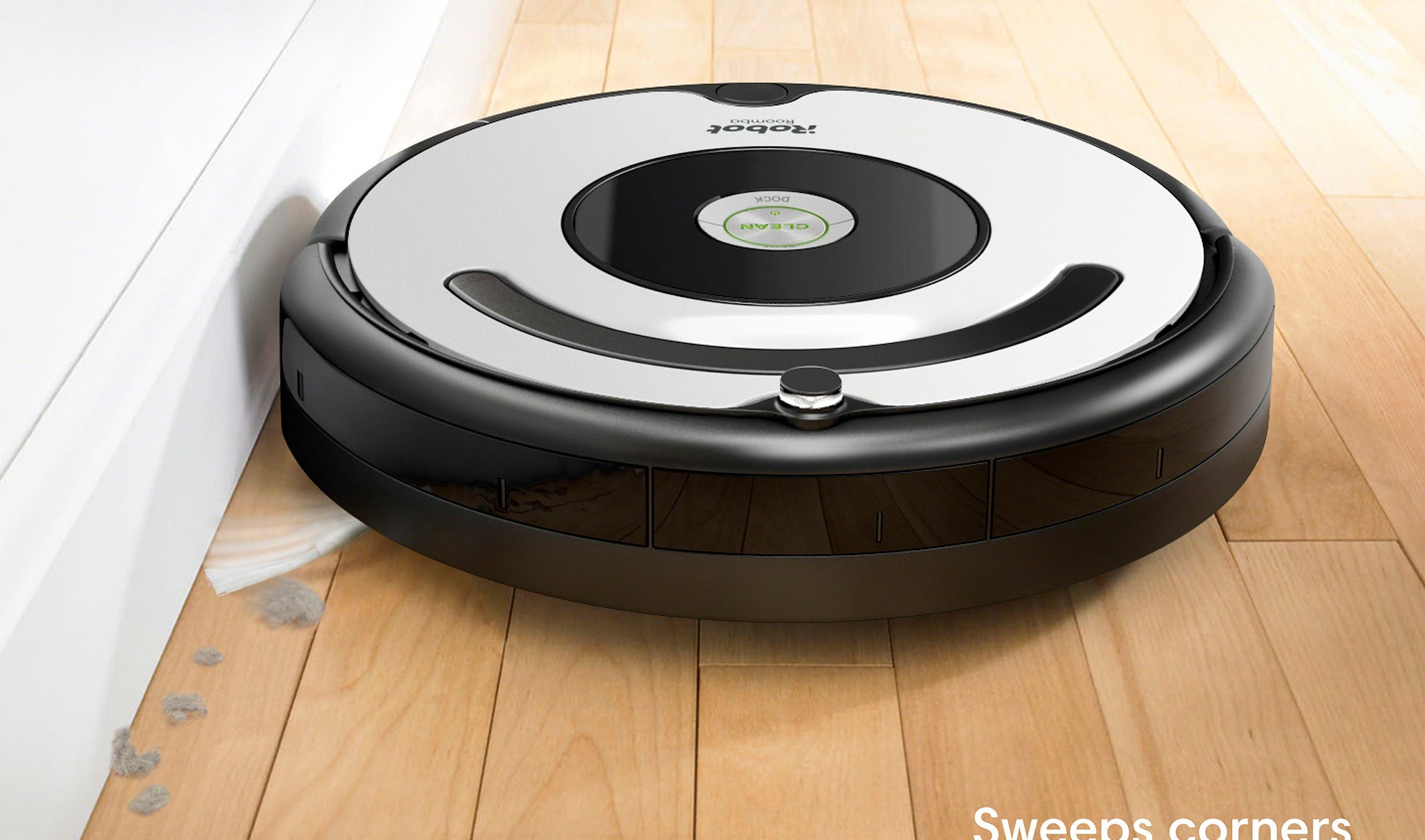 roomba robot vacuum sweeping up dust against a wall