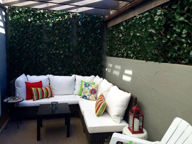 A small patio with the artificial greenery screen surrounding it on two sides.