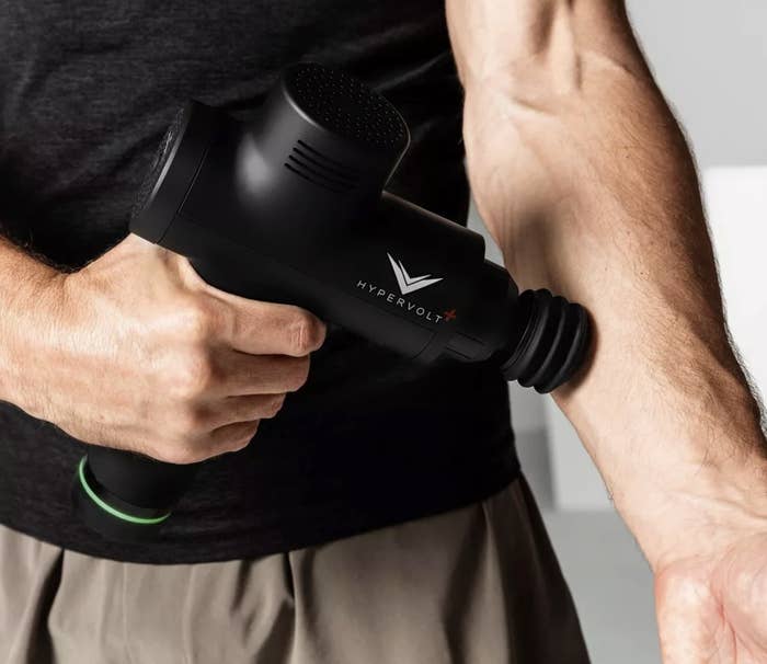 Model is holding a black motorized body massager against their forearm