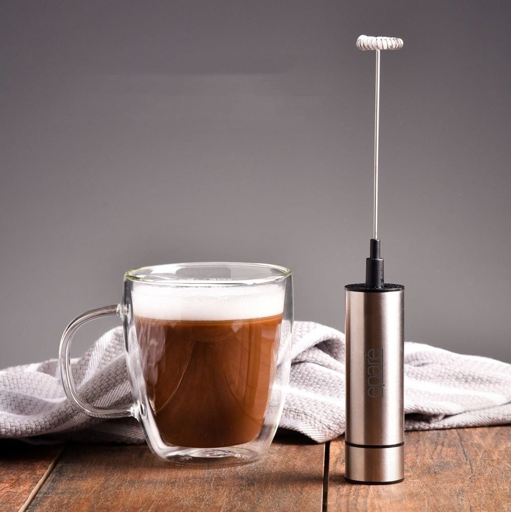 a milk frother next to a cup of coffee