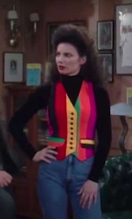 Fran Fine wearing jeans, a black turtle neck shirt, and a rainbow vest.