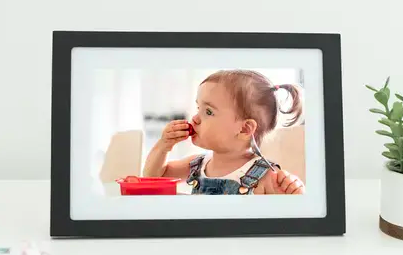 Child eats piece of fruit in photo shown on black-and-white, digital Skylight Frame