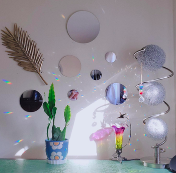 Reviewer shows mirror circle display above their dresser with a tiny plant pot and shimmery disco decoration