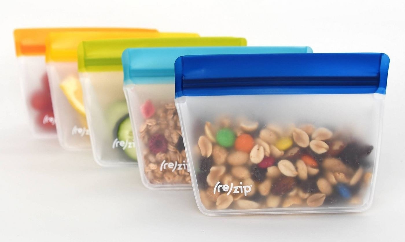 five reusable storage bags with various snacks in them