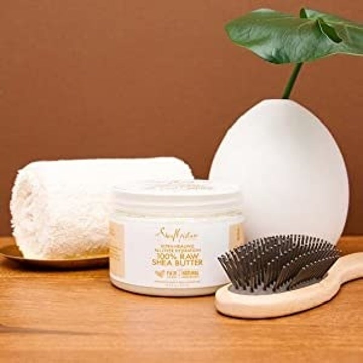 the shea butter next to a hair brush and towel