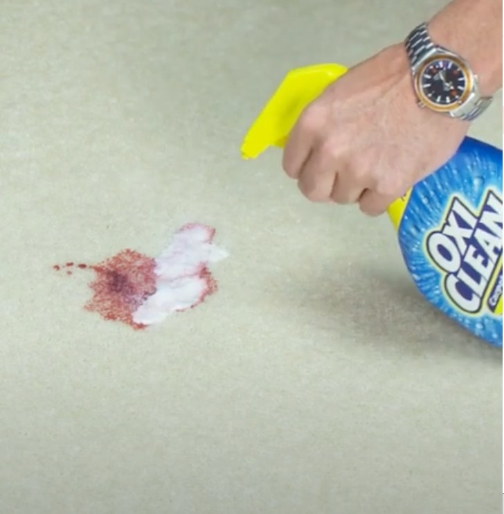 A model spraying OxiClean on a wine stain