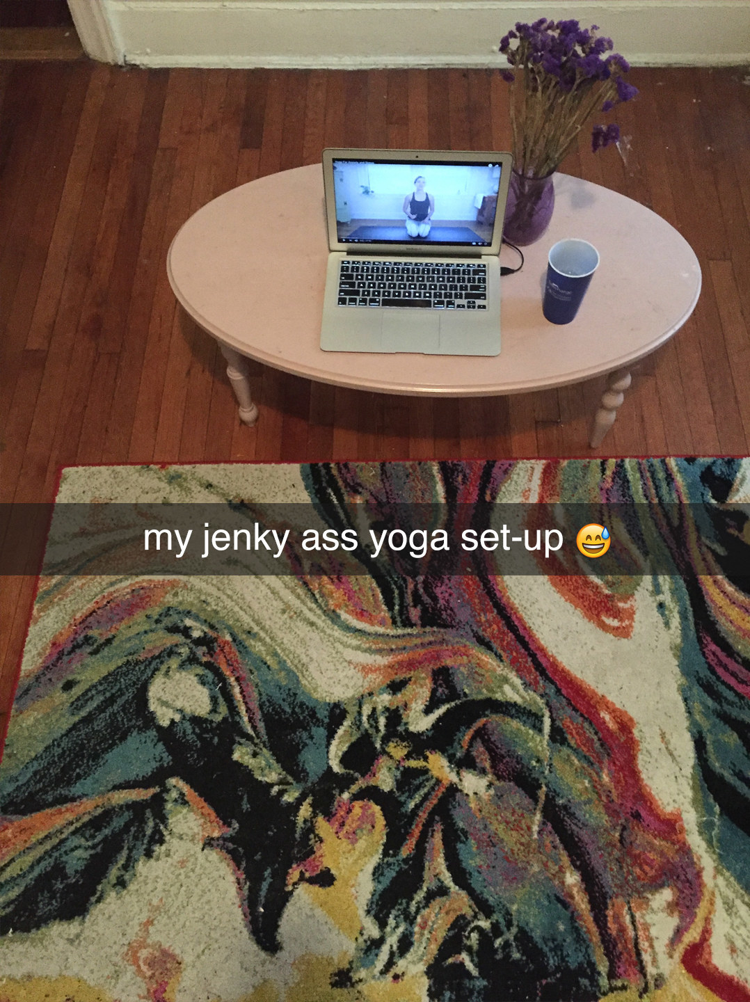 A person&#x27;s living room with a rug and laptop on a coffee table captioned, &quot;My jenky ass yoga set-up&quot;