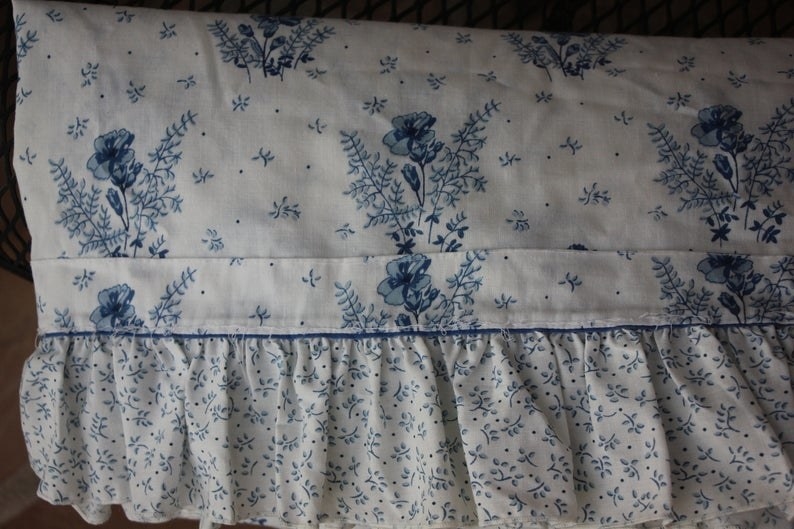 A blue and white flower pillow case with a ruffle