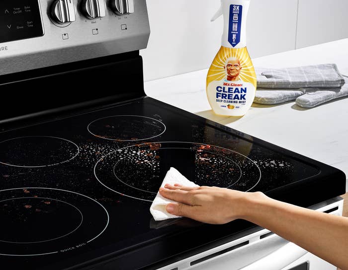 A model wiping food off of a glass stovetop