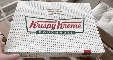 Krispy Kreme box filled with 12 doughnuts being opened