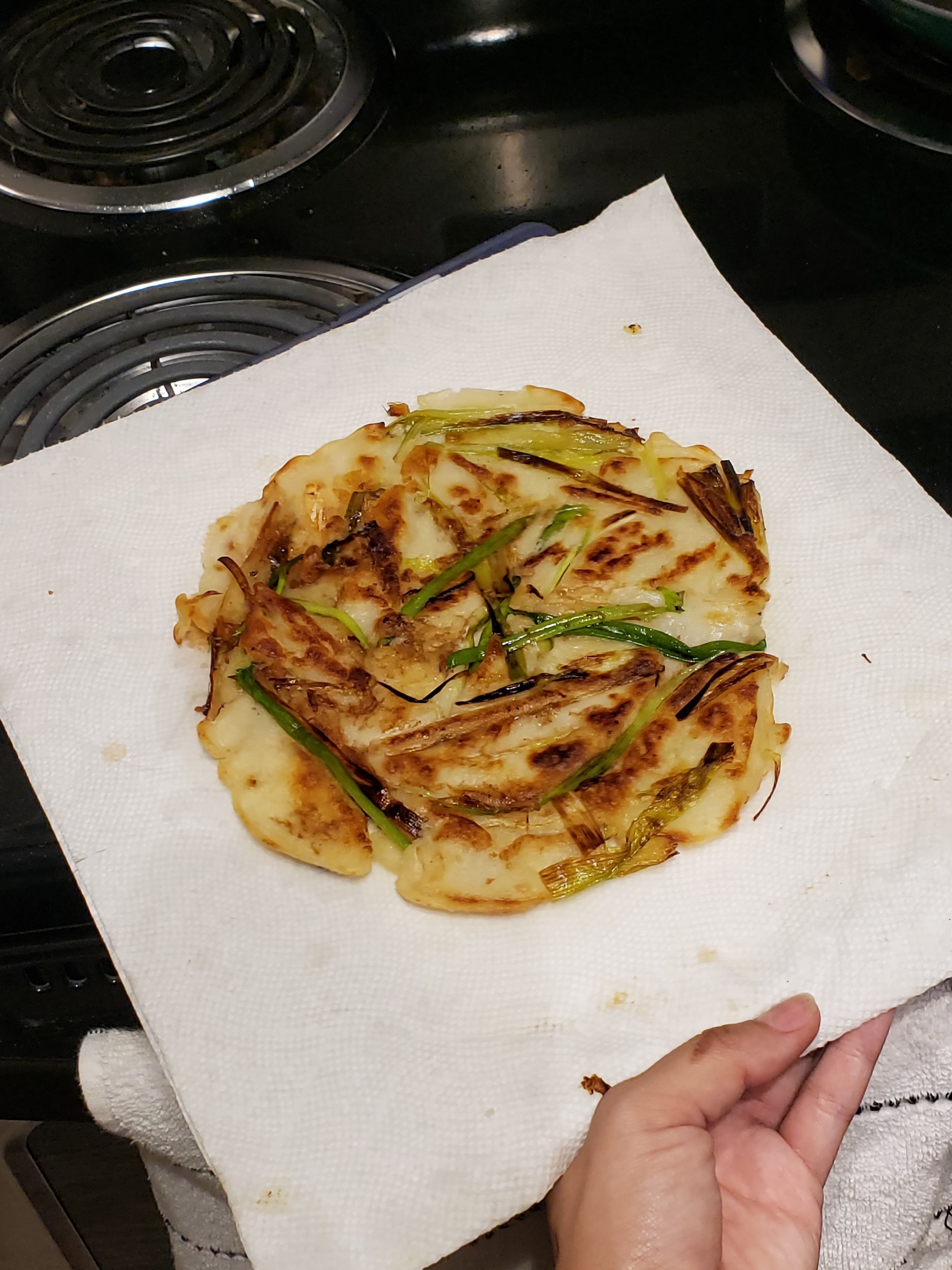 The finished golden brown pancake on a paper towel over a cutting board