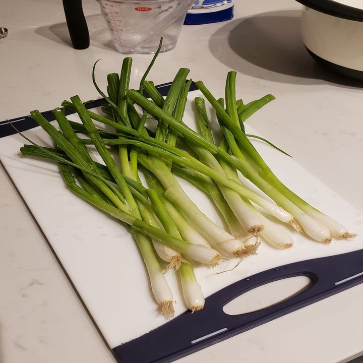 Uncut, raw scallion stalks laying on a cutting board