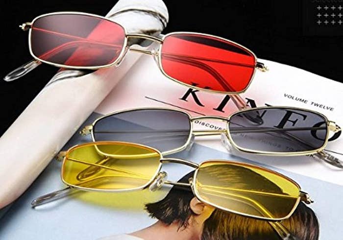 Three thin-rimmed retro sunglasses in the colours red, black and yellow displayed on a magazine.