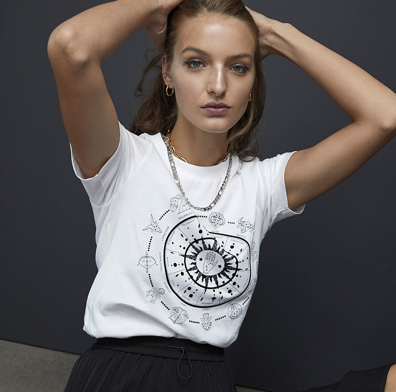 A person wearing the zodiac shirt with a high-waisted skirt