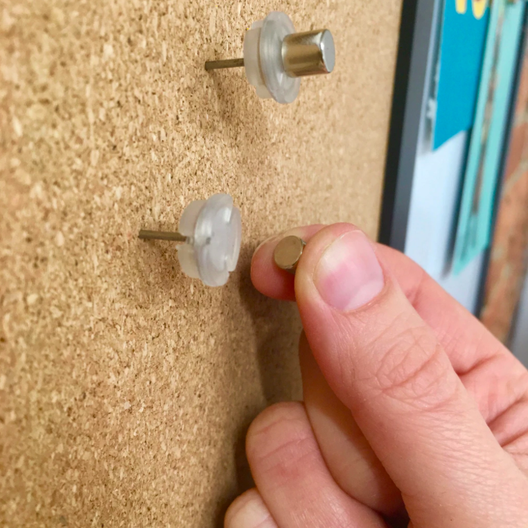 A person holding the magnetic piece next to the pushpin piece