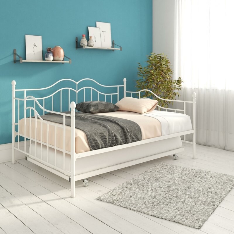 A twin sized day bed with a metal frame with one mattress on top and a second frame underneath it that can slide a second mattress out as well 