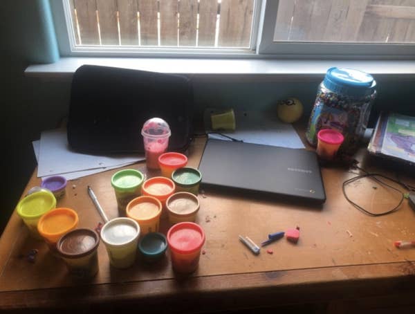 A messy at-home school desk covered in playdough and erasers,