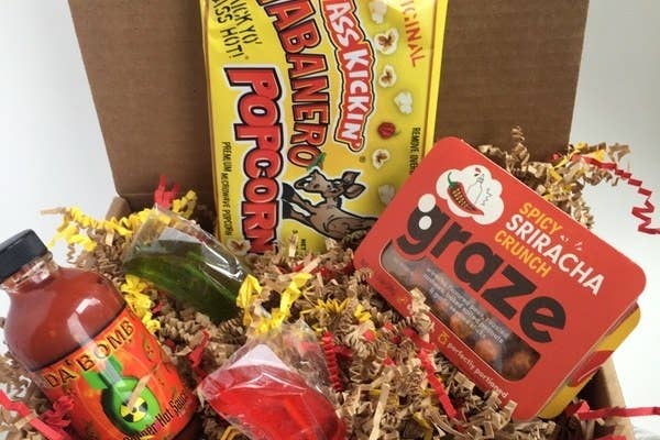 The Scorchin&#x27; Hot Box filled with spicy items like a bottle of hot sauce, a Grace spicy sriracha crunch snack, habanero-flavored popcorn, and more