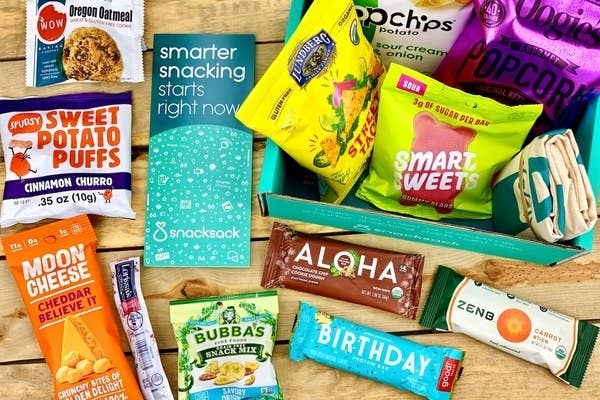 Various snacks you may find in a SnackSack box like cinnamon churro sweet potato puffs, cheddar moon cheese, and sour cream & onion popchips