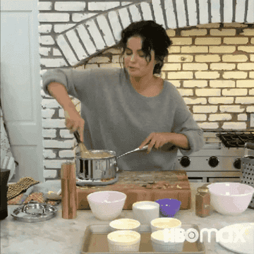Selena Gomez stirring something in a saucepan with a whisk on her show &quot;Selena + Chef.&quot;