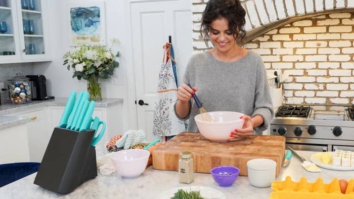 Selena Gomez on the set of her cooking show, Selena + Chef, whisking eggs in a mixing bowl.