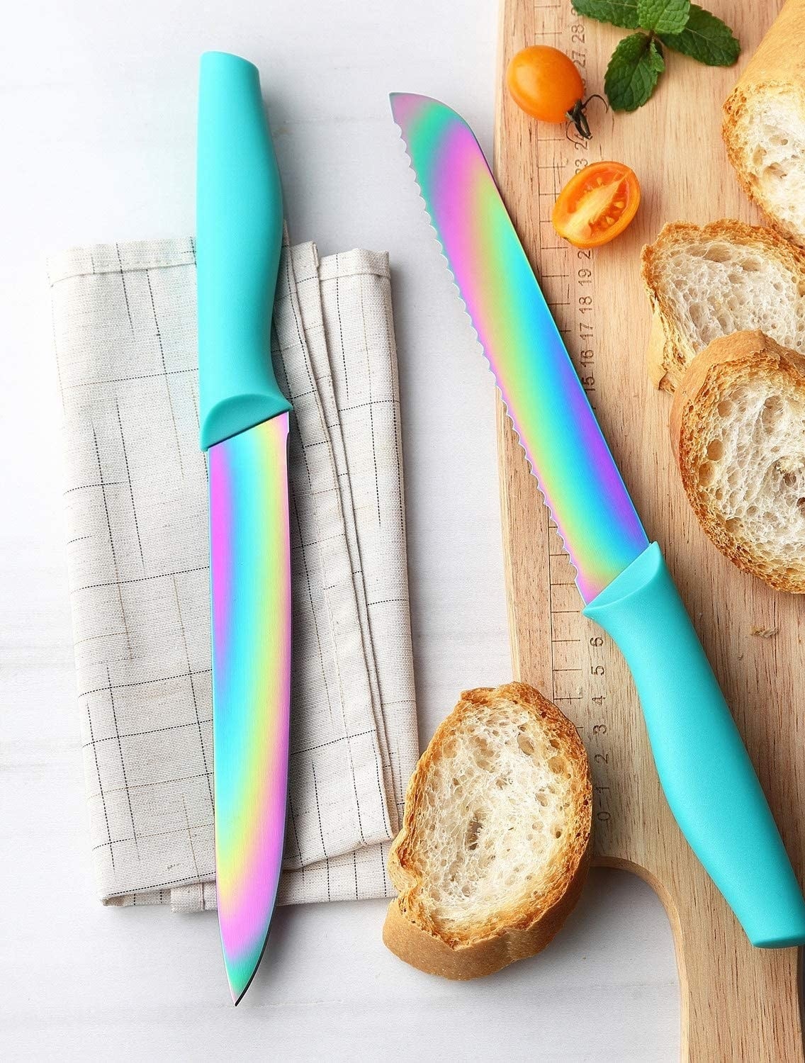 Two rainbow knives with turquoise handles and sliced bread on a cutting board.