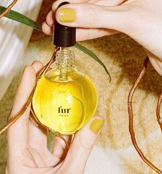 model holding clear round bottle with clear dropper and yellow liquid inside