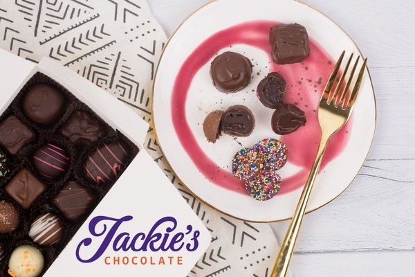 A box of Jackie&#x27;s Chocolate next to a plate with some of the chocolates on it