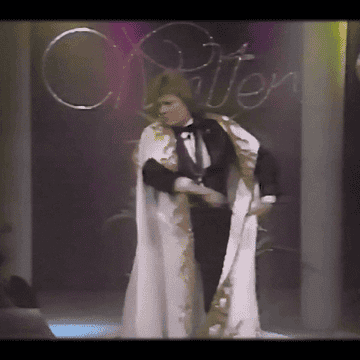A GIF of alter Mercado spinning in a white and gold cape