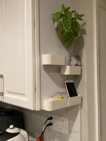 Reviewer pic of three shelves on the side of a white cabinet with a phone and other small trinkets in them
