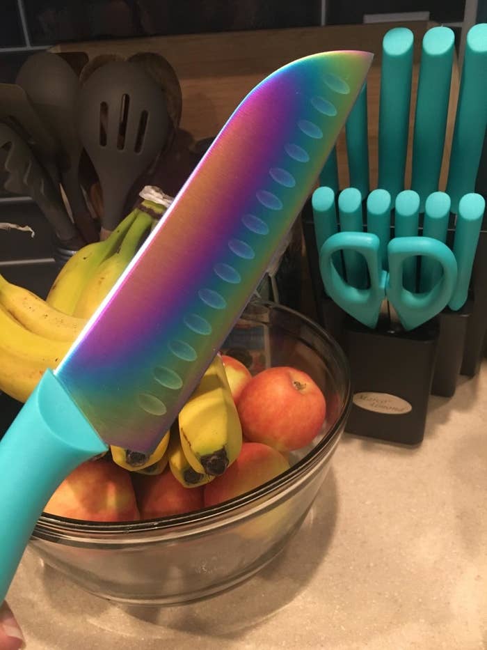 一只手拿着彩虹在厨房里厨师刀水果盘。