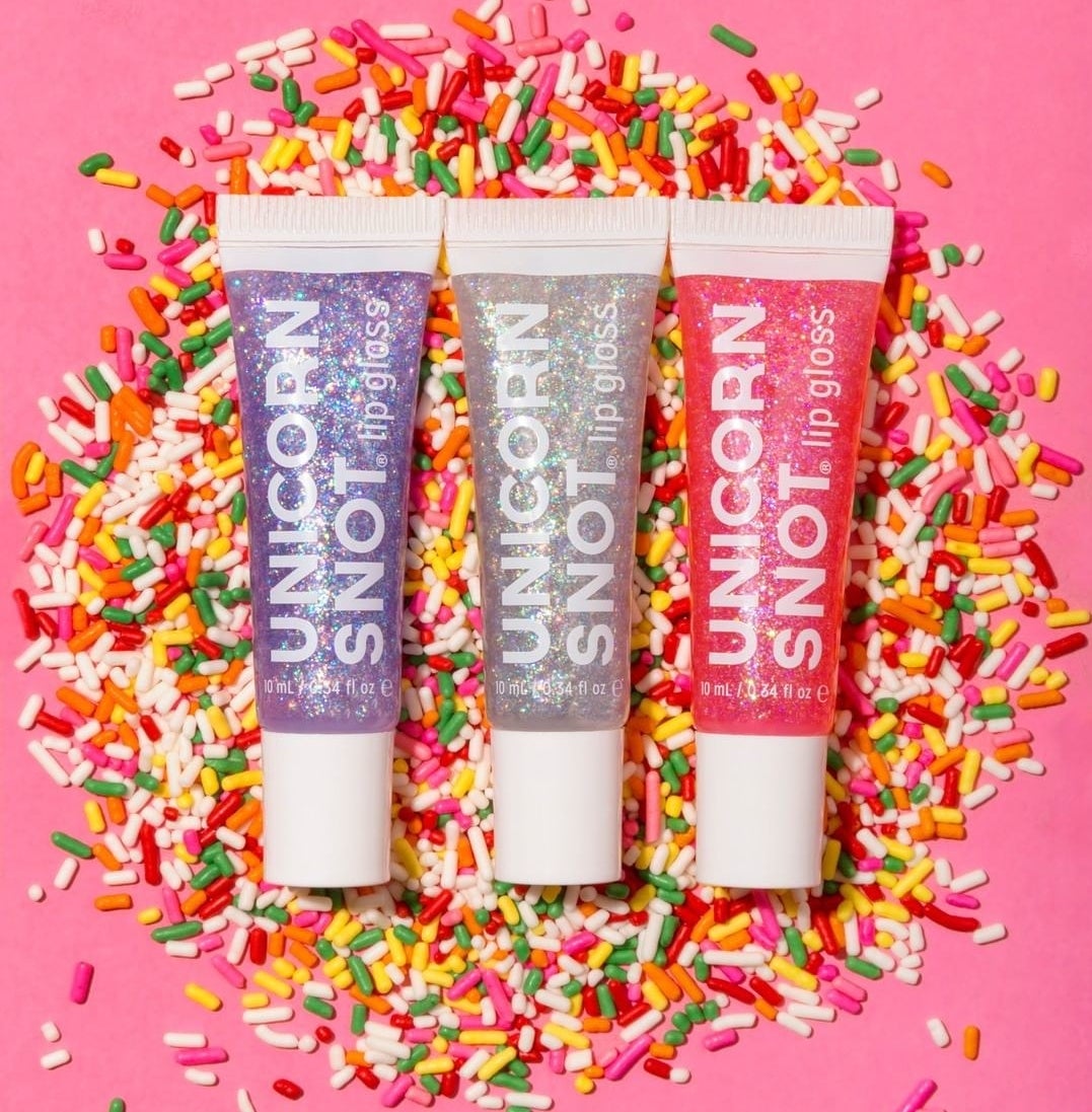 Three holographic lip glosses on a pile of sprinkles