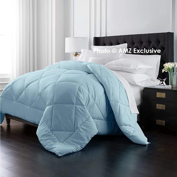 An ice blue comforter pictured on a bed.
