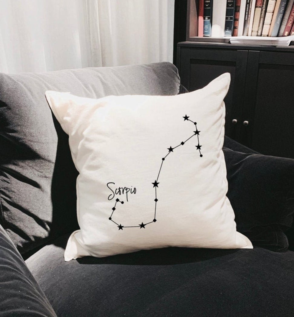 A throw pillow with the zodiac cover on it on a chair
