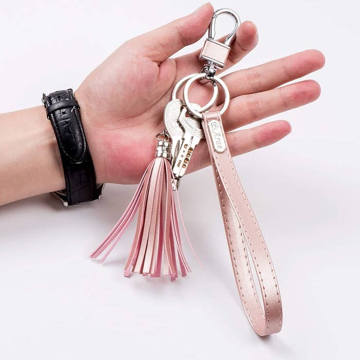 A person holding the lanyard key chain with keys on it