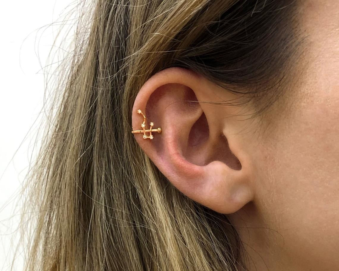 A person wearing a constellation ear cuff on their upper ear