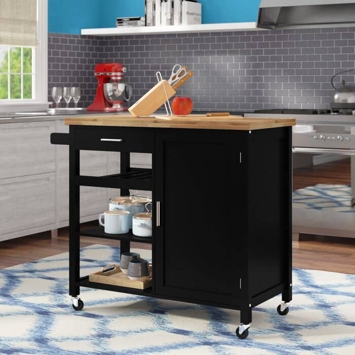 The Domenique Kitchen Cart Solid Wood storing pots and pans in a display kitchen