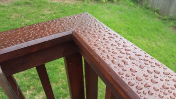 Reviewer photo of railing on their deck showing the treatment is repelling water droplets