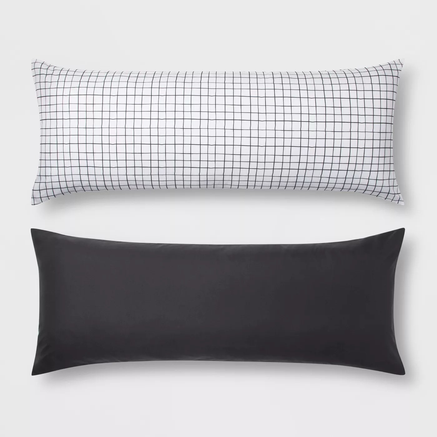 A white body pillow with a black, checkered print and a solid black body pillow