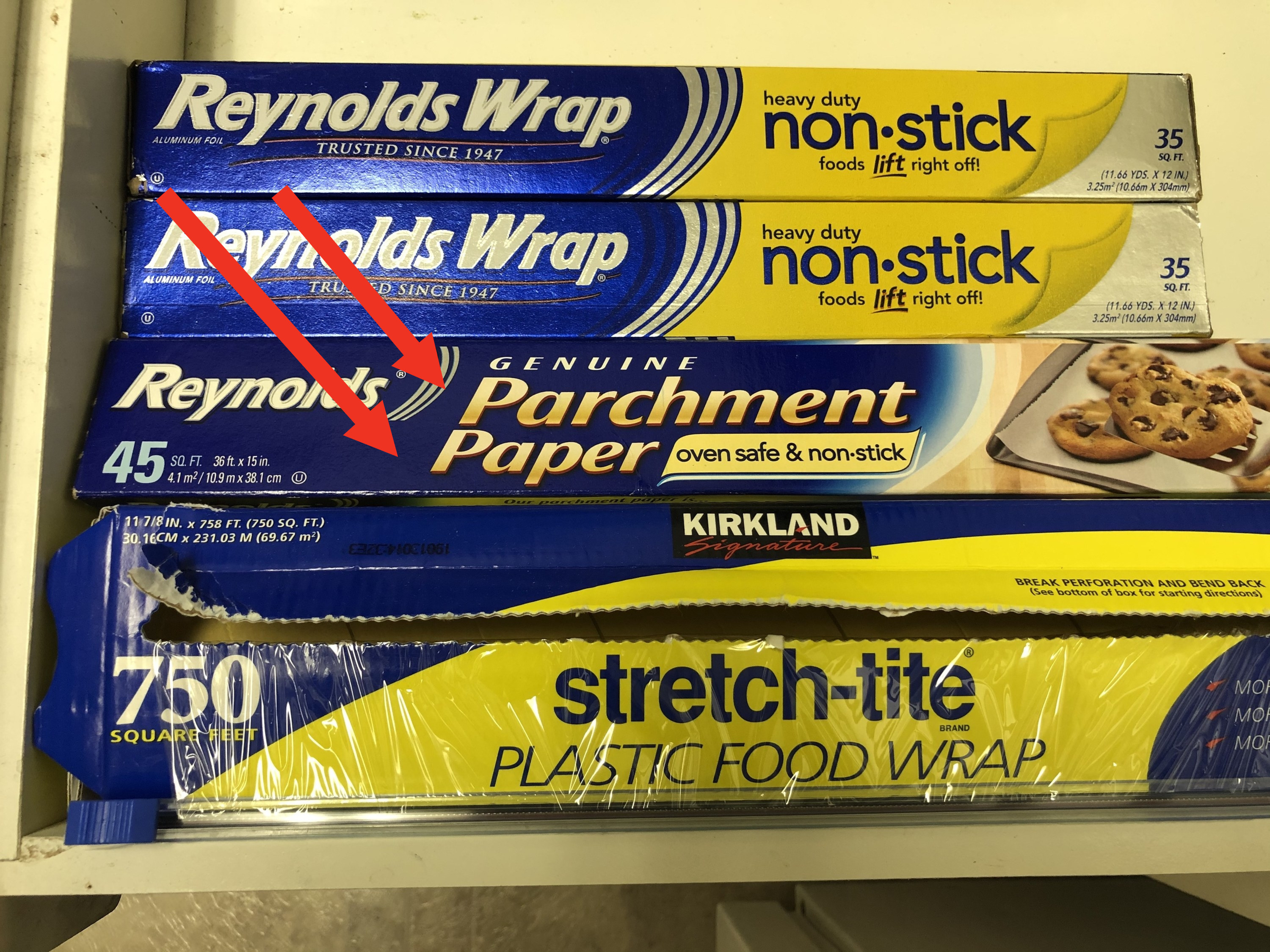 A kitchen drawer containing parchment paper and tin foil rolls.