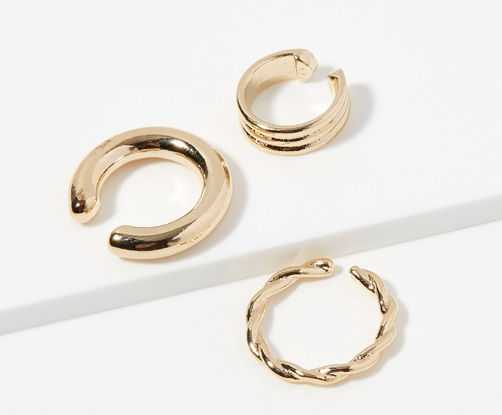 Three gold ear cuffs that are different sizes