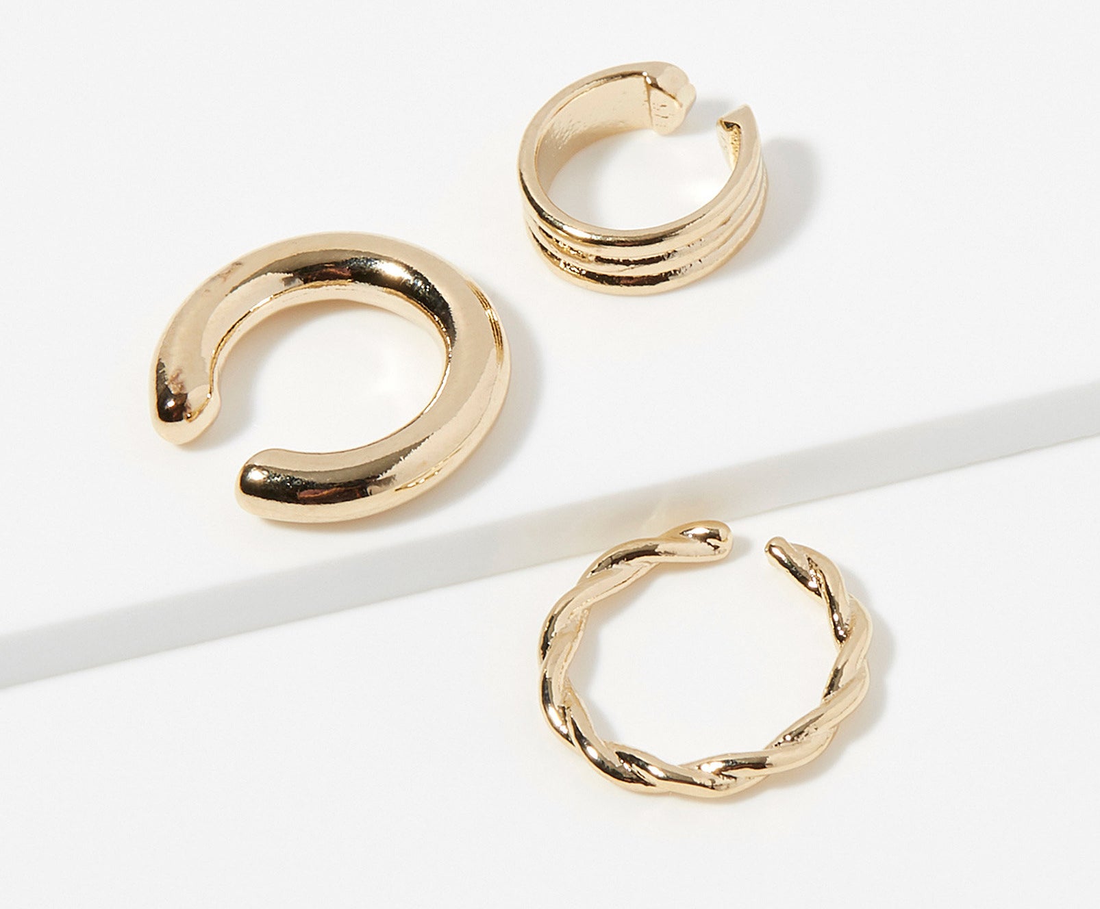 Three gold ear cuffs that are different sizes