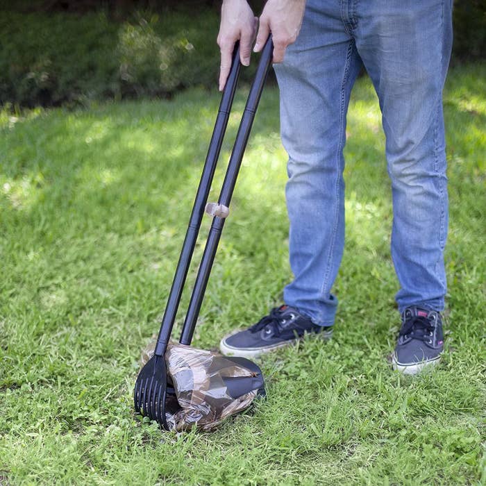 Pet owner uses pooper scooper to tidy up yard