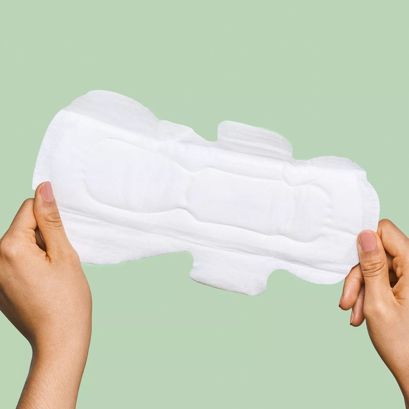 A model holding a menstrual pad lengthwise to show the wings and the shape of the pad