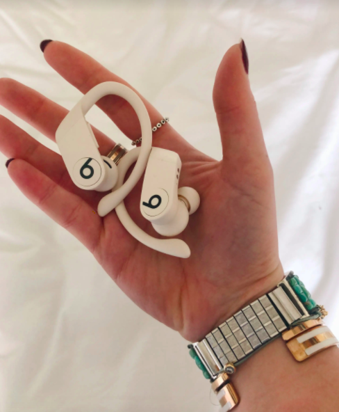 BuzzFeed editor Emma McAnaw holds pair of white Powerbeats Pro Wireless Earphones in their hand