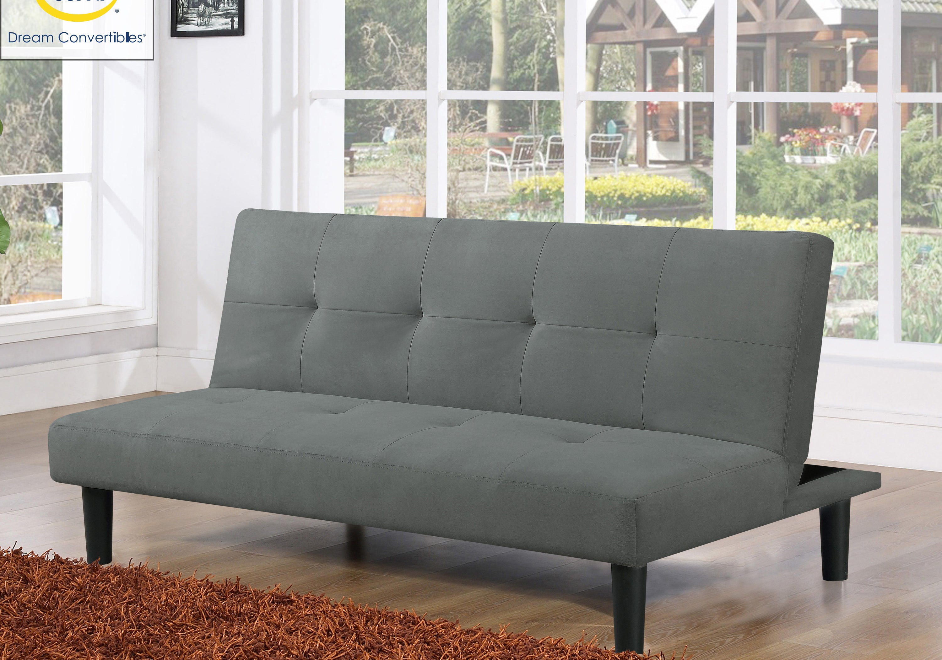 The grey futon in front of a large window