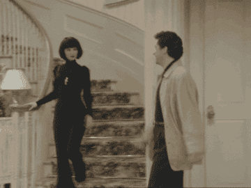 Fran Fine, walking down the stairs wearing an all back outfit and greeting Mr. Sheffield.