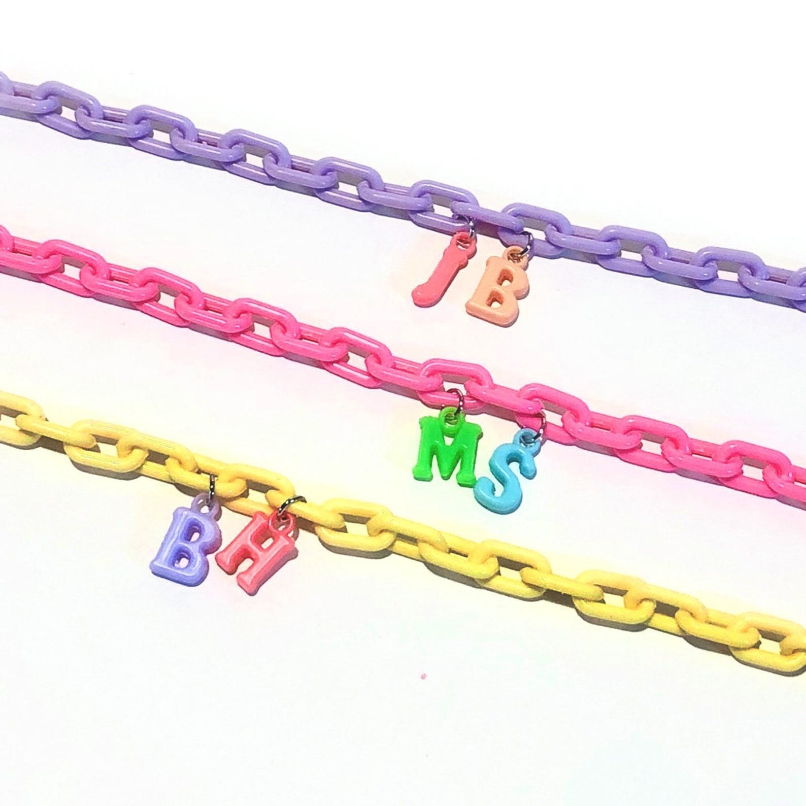 Bright yellow, pink, and purple chains with brightly-colored initial charms 