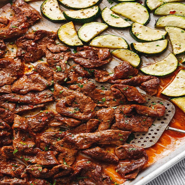 Cooked beef with lemon zucchini on a sheet pan.
